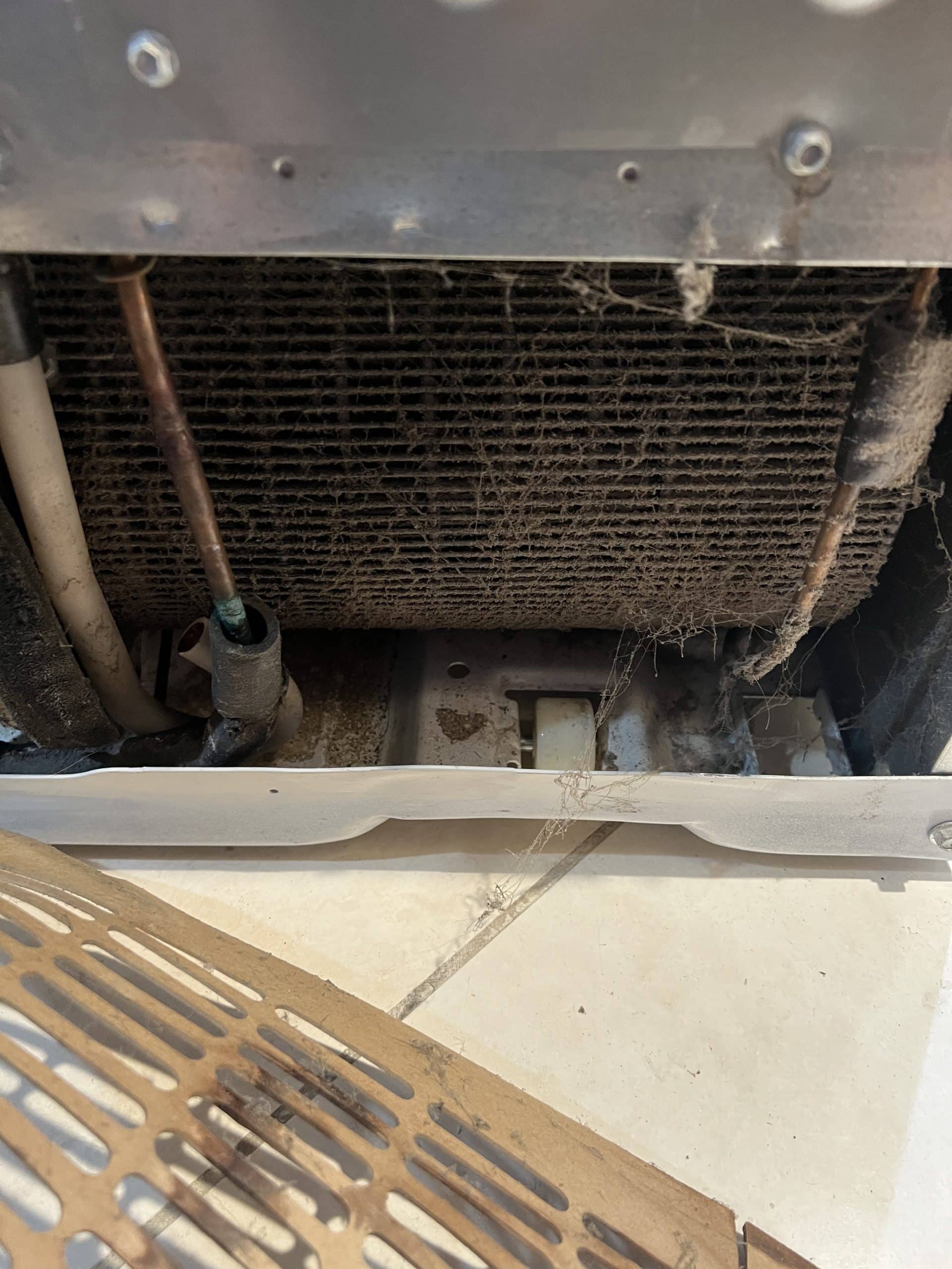 Refrigerator condenser blocked with dirt and debris.