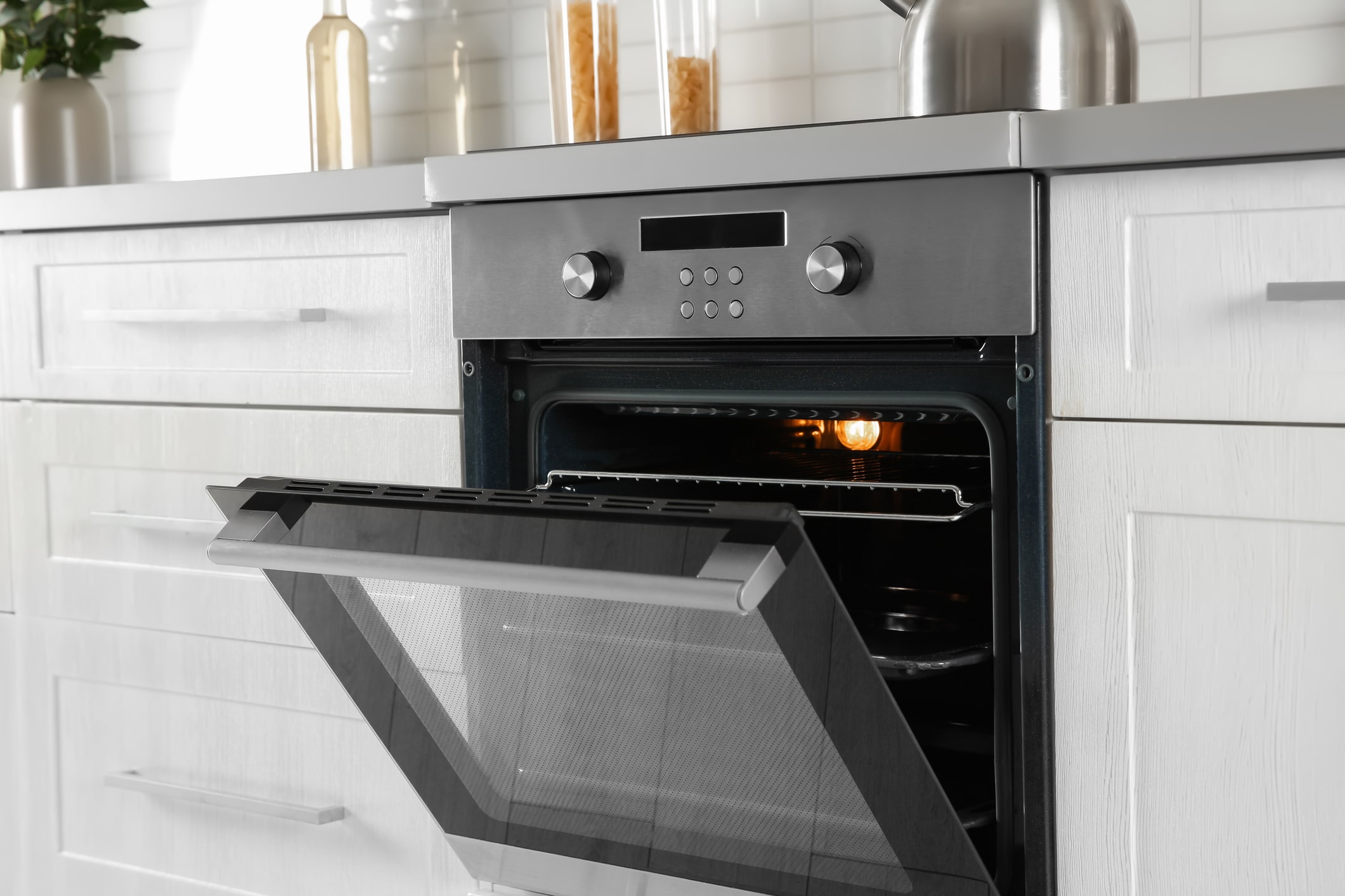 Modern kitchen oven with open door and light on.