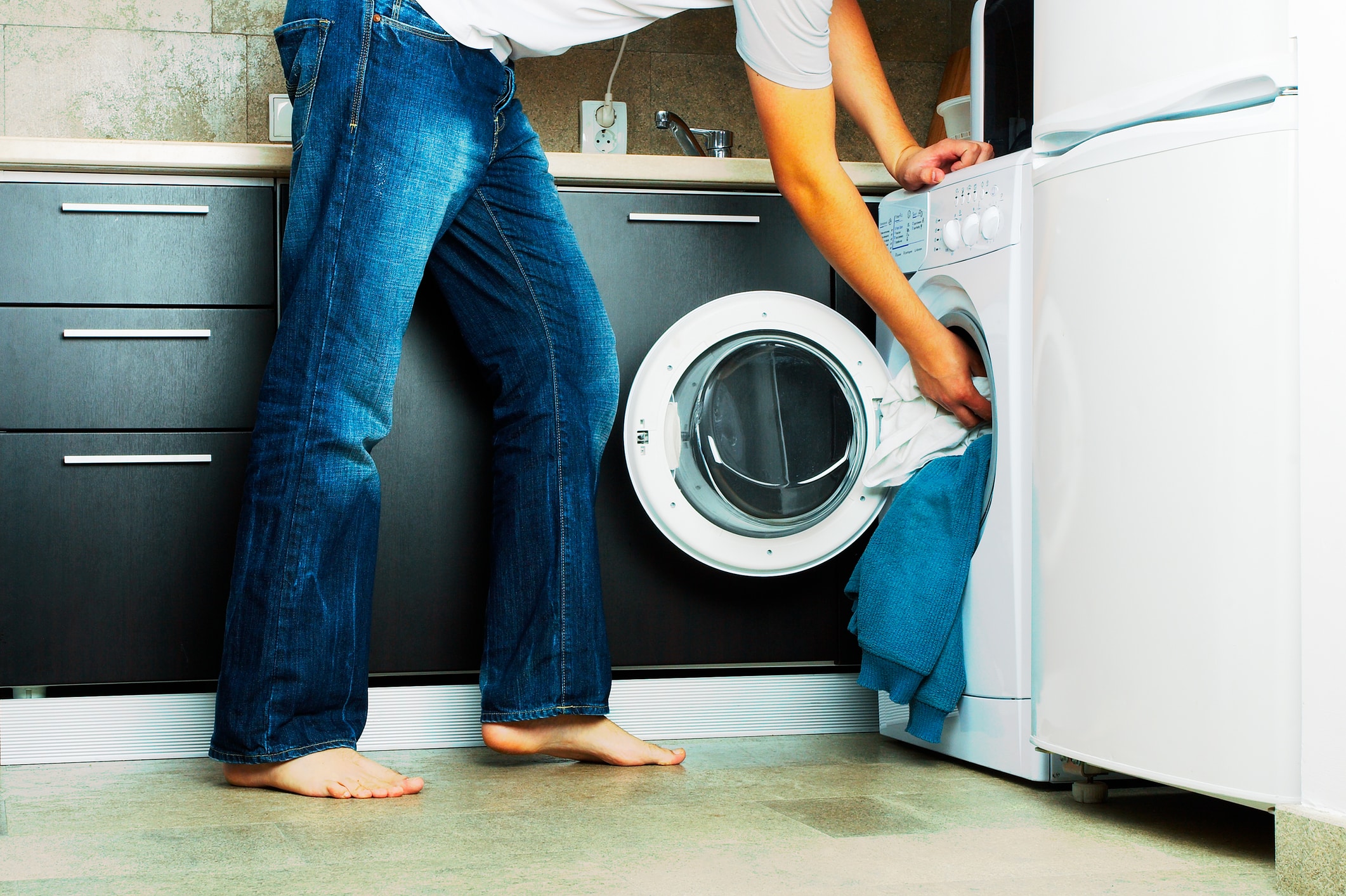 Person loading clothes into washing machine
