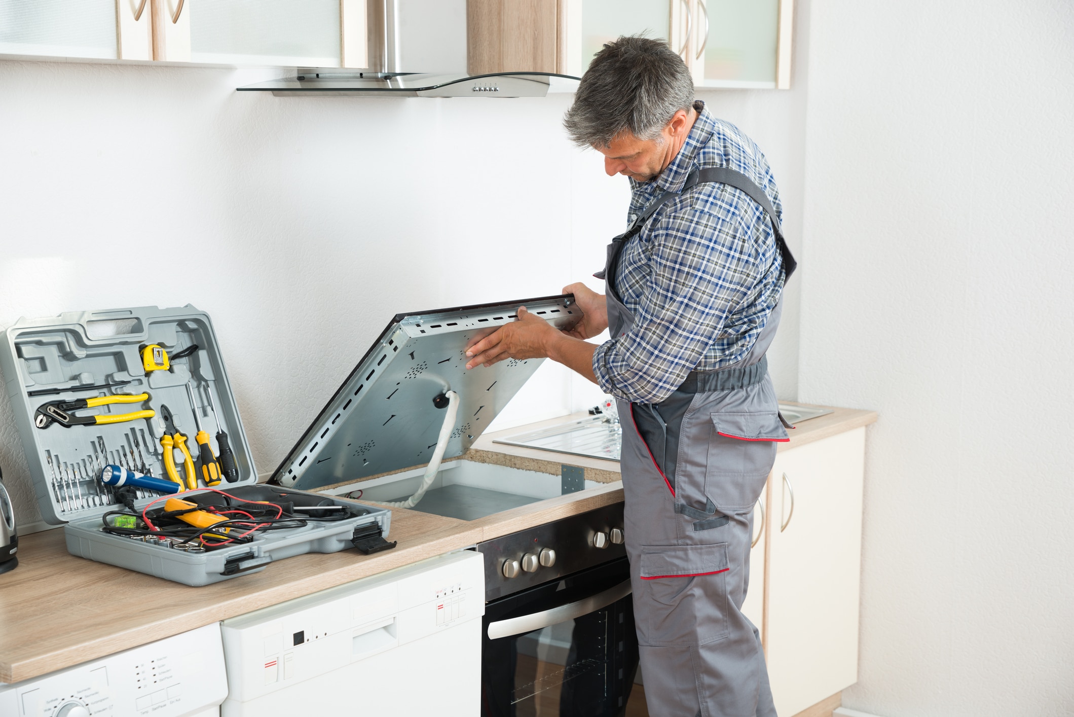 Appliance technician performing stove repair in Woodland Hills kitchen with professional tools