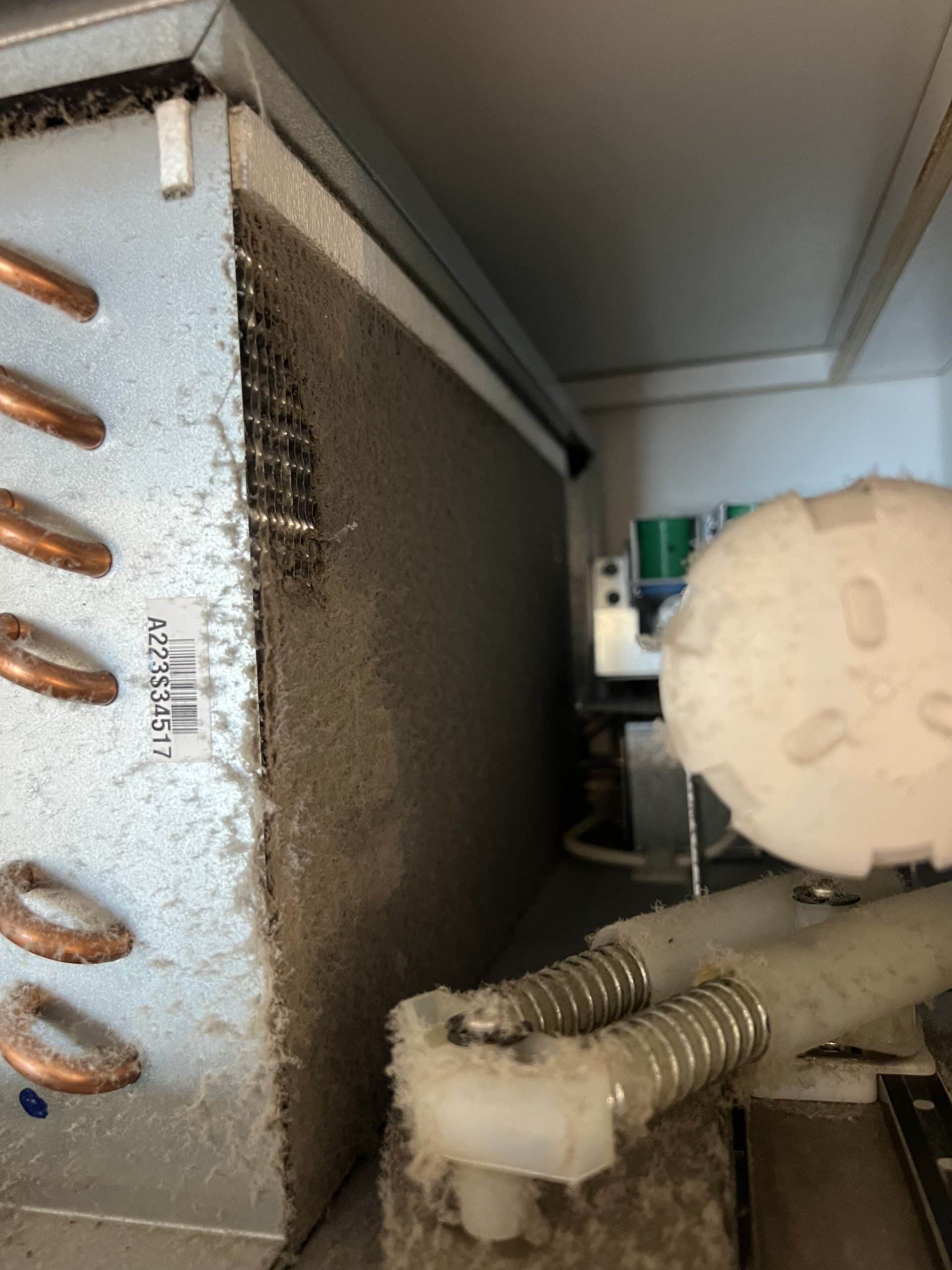 Dusty refrigerator coil and components inside