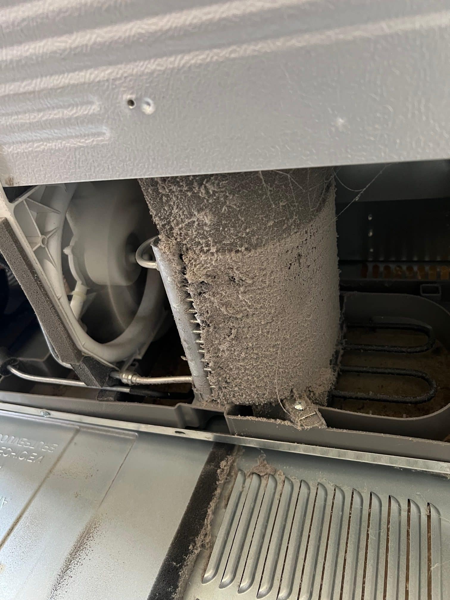 Dusty appliance interior with lint buildup.