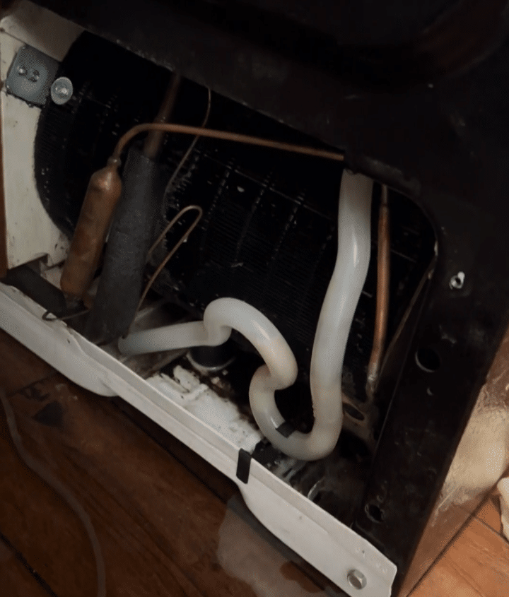 Open refrigerator back panel with visible tubes.